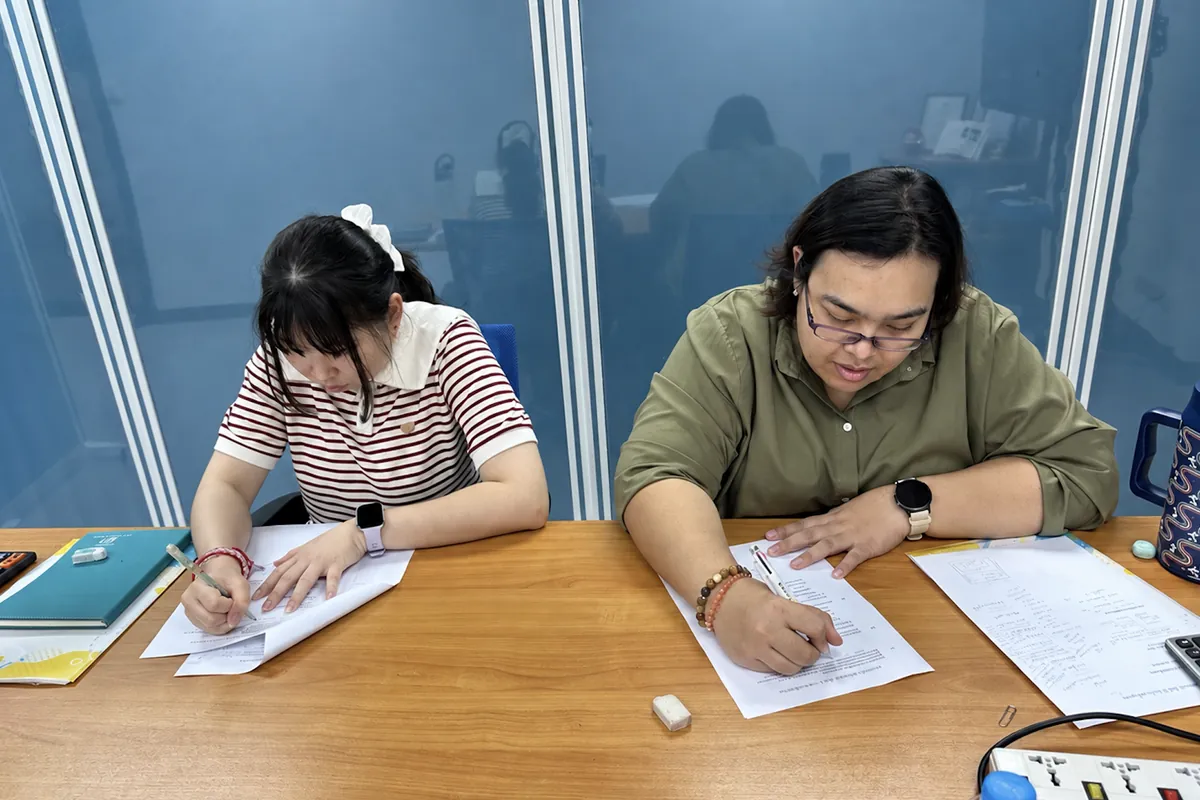 タイ語の教材で演習問題に取り組むタイ人スタッフ